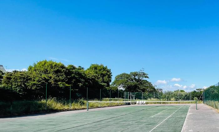 Tennis Court at Ysgubor Degwm self catering holiday let in North Wales. Hard surface tennis court painted green with blue sky